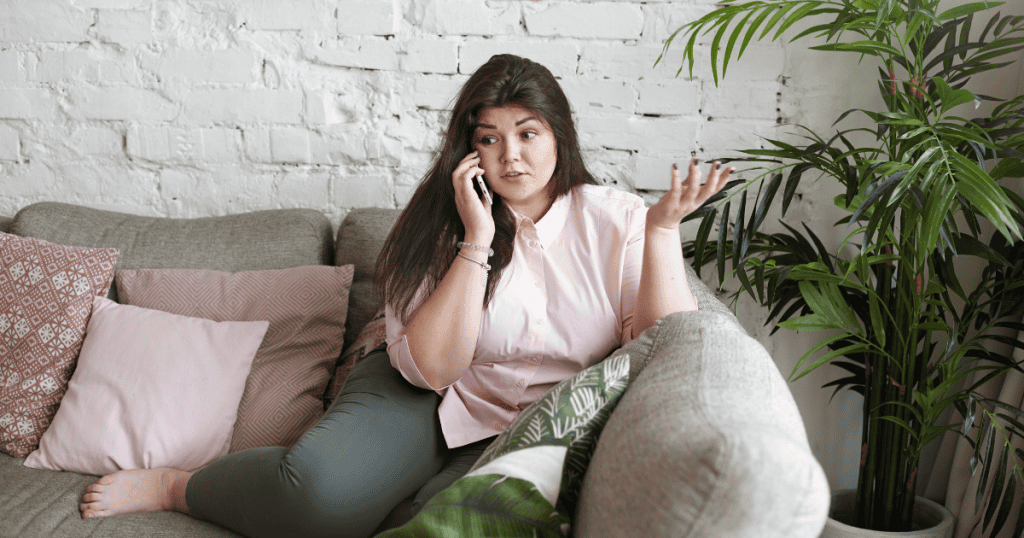 A woman on the phone shrugs with calm confidence, embodying the boundary-setting attitude behind the phrase, “If my no offends you, your expectations are the problem.”