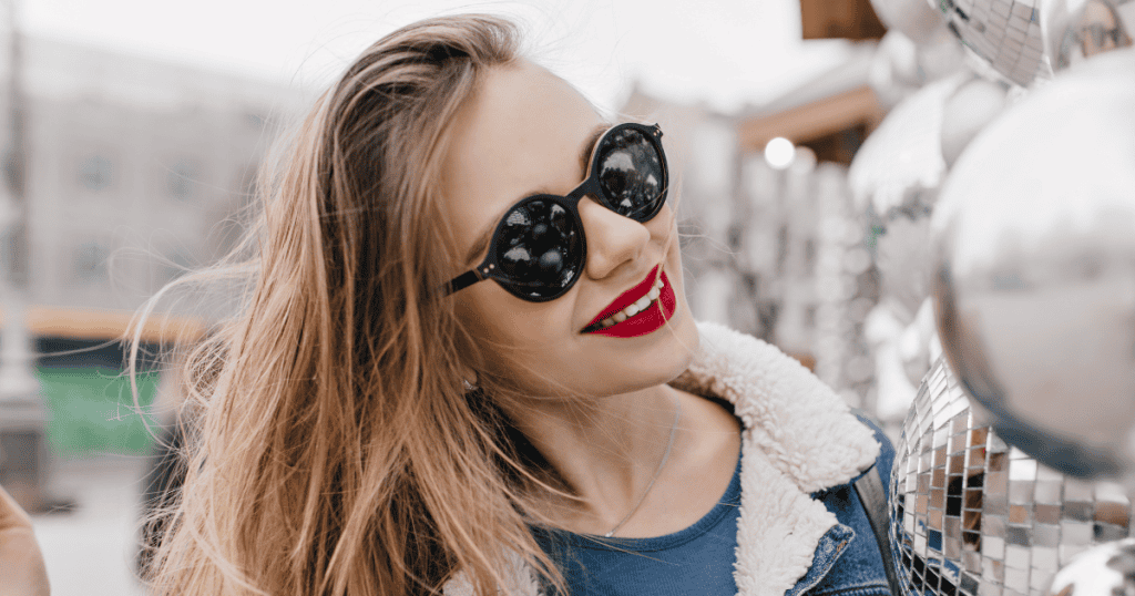 A smiling woman in bold red lipstick and sunglasses exudes carefree confidence, symbolizing the power to shut down guilt trips and stand firm.