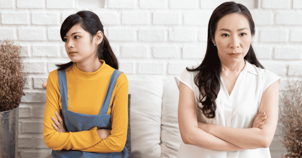 A young woman and an older woman sit beside each other with crossed arms and tense expressions, showing the cold, calculated dynamic of narcissistic abuse within families.