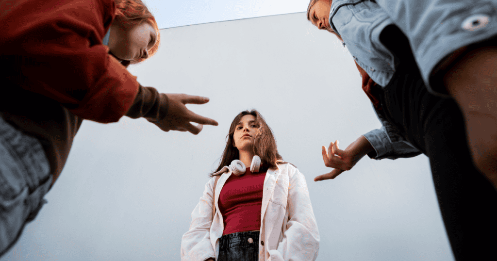 A young woman stands confidently with headphones around her neck while two others gesture at her, representing how boundaries donโt push people awayโthey push narcissists out.