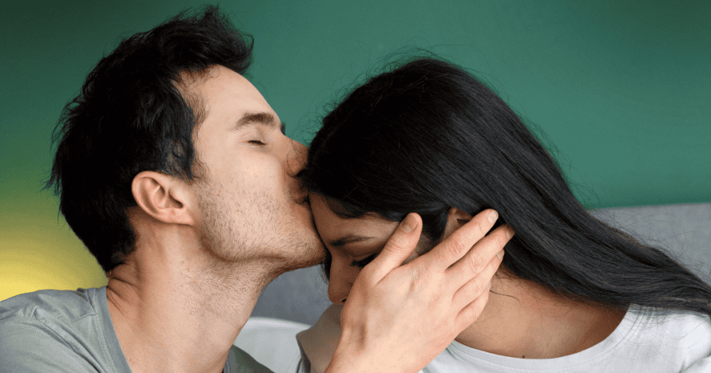 A man kisses a woman on the forehead while holding her head gently, symbolizing that even being “perfect” wouldn’t save them.