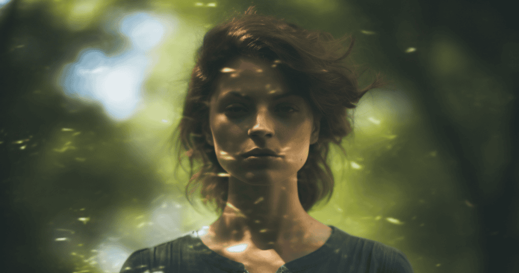 A woman stands in soft, dappled light surrounded by nature, her calm yet defiant expression reflecting how healing can appear rebellious to those who don’t understand it.