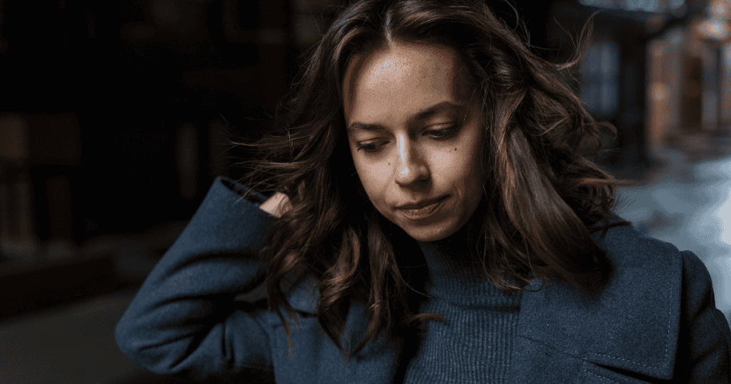 A woman walking alone with a somber expression, reflecting the realization that the pain caused by a narcissist was never her fault.