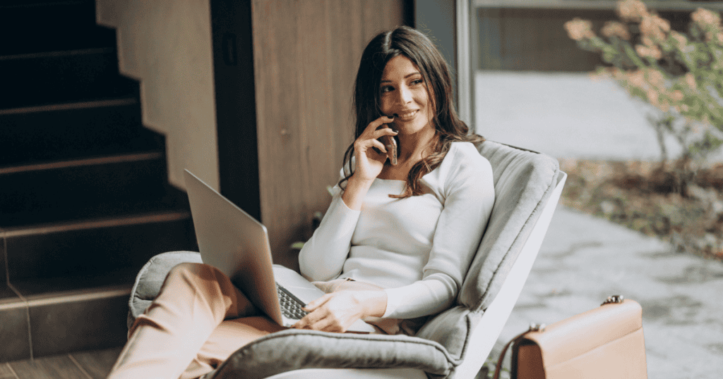 A woman sits comfortably with a laptop on her lap and phone in hand, embodying the polite confidence it takes to say no to a narcissist while staying gracious.