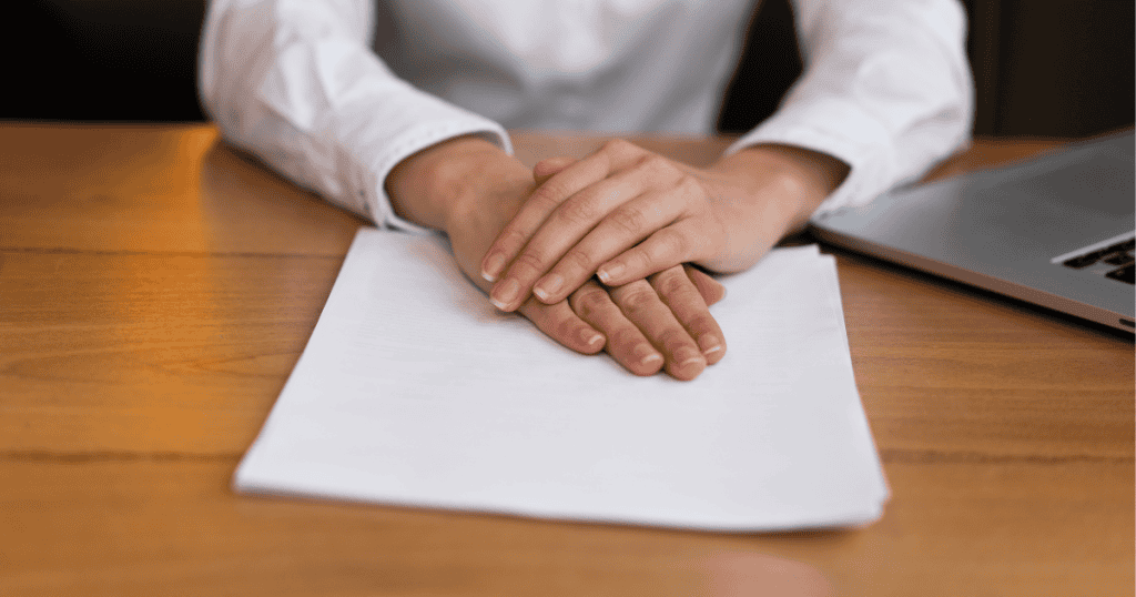 A person rests their hands on a stack of papers beside a laptop, symbolizing that obligation isn’t a contract to tolerate abuse.