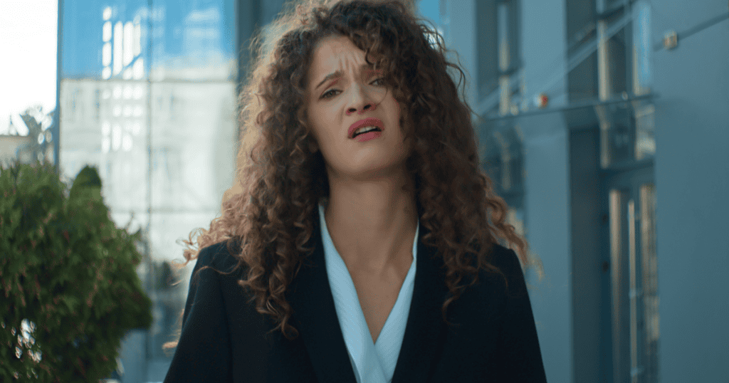 A distressed woman outdoors in business attire, reflecting how narcissists use reactions to impose false guilt.