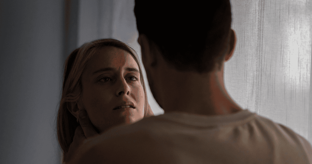 A distressed woman looks up at a man holding her face, representing the relentless cycle of cruelty that defines a narcissist’s abuse.