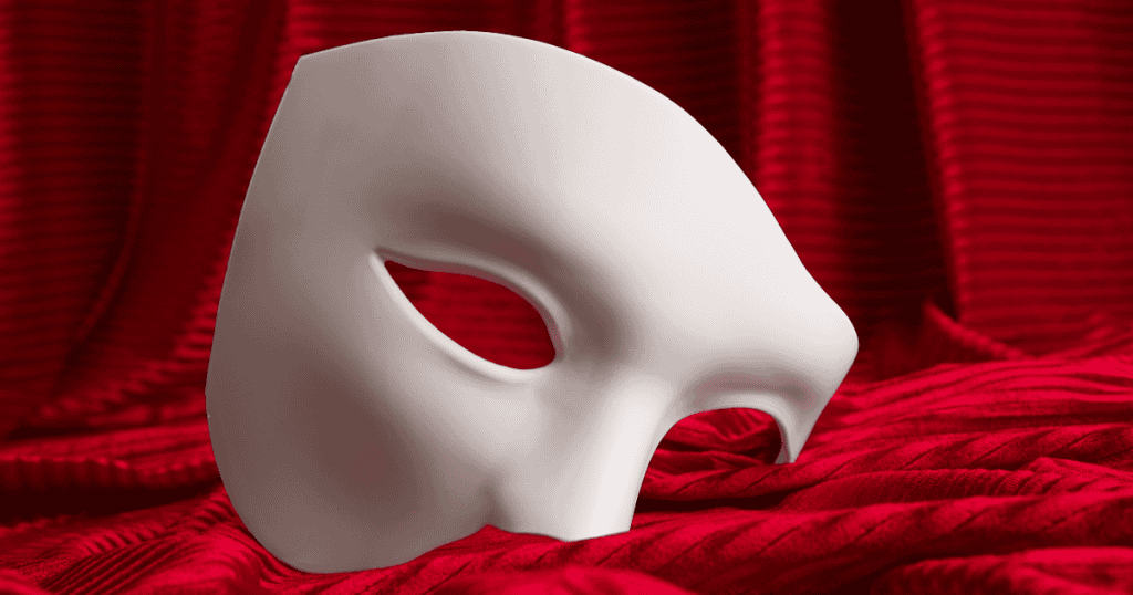 A white half-mask rests on red fabric, symbolizing the deceptive façade a narcissist wears during the early stages of love.