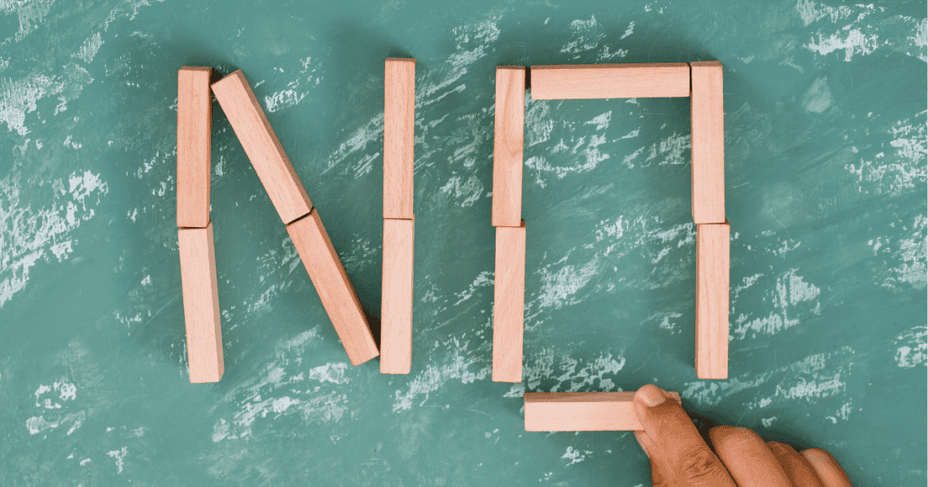 Wooden blocks arranged to spell the word โNOโ on a green surface, representing the โNoโ boundary.