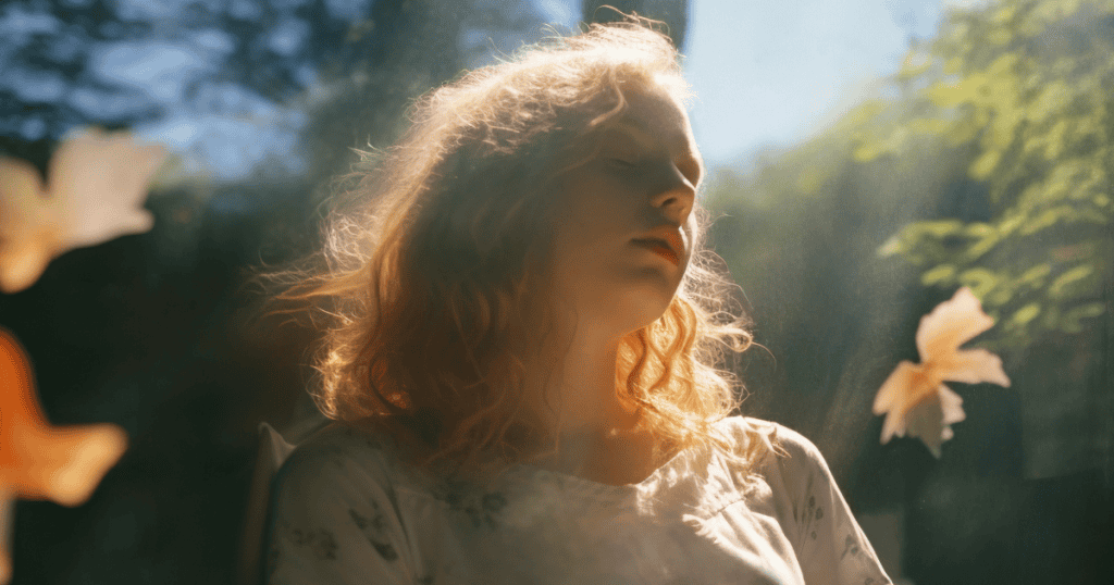 A woman sits quietly by a window with sunlight illuminating her face, symbolizing healing and self-reflection after enduring survival mode.