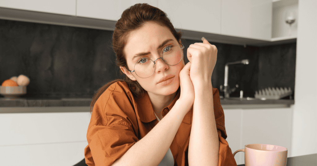 A woman sits at a table with a steady, unapologetic expression, her posture exuding strength and conviction, a striking reminder of the power and sanctity of standing by one’s boundaries.