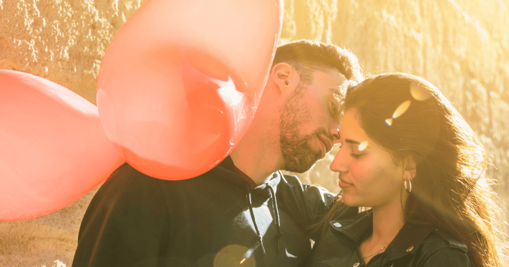 A couple stands close together in warm sunlight with balloons behind them, reflecting how a narcissist’s version of “love” can appear tender while masking abuse.