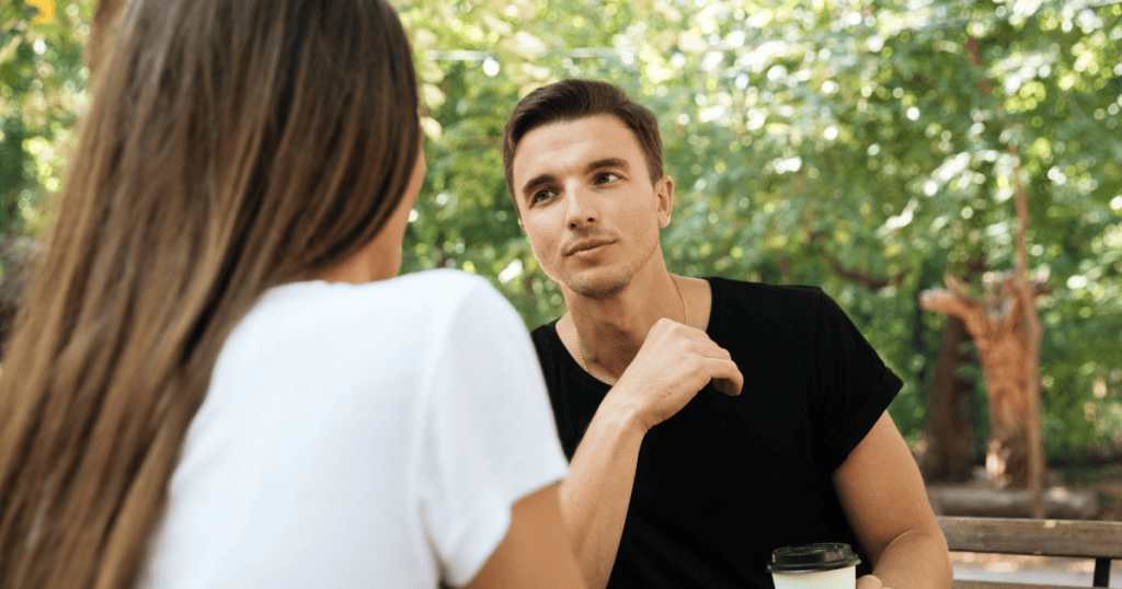 A man leans forward at a table to look intently at a woman across from him, suggesting a constant readiness to engage with others outside of a committed bond.