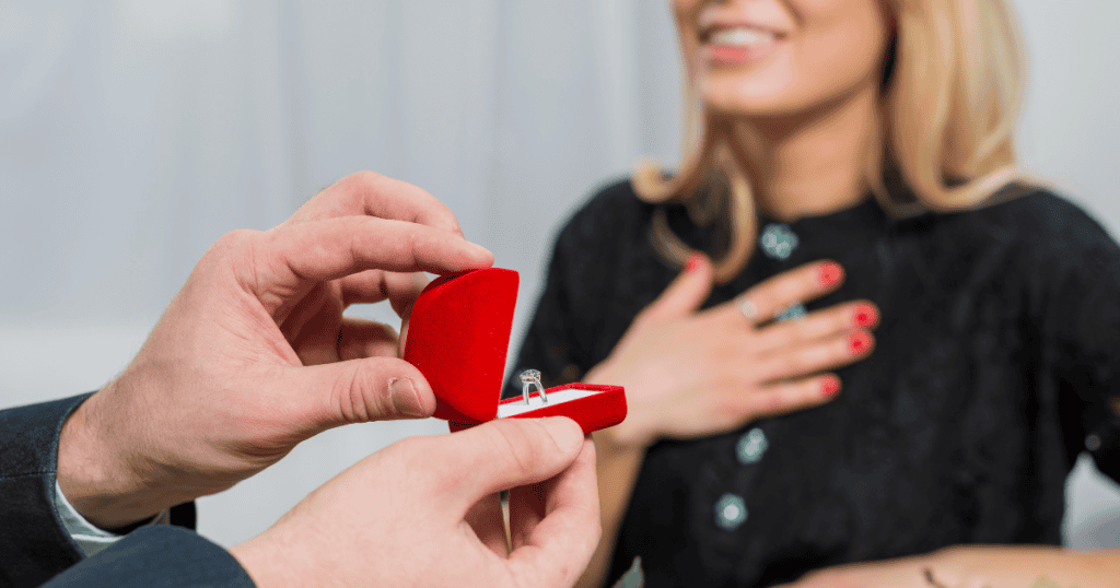 A close-up of a person presenting an engagement ring to a surprised partner, showing a grand gesture that might serve as a mask for underlying issues.