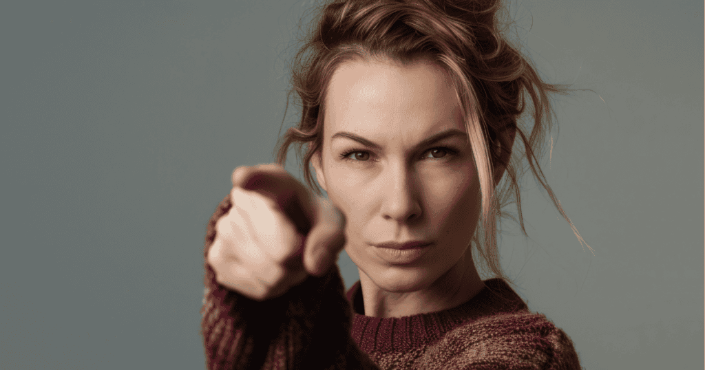 A serious woman points an accusing finger directly at the camera, capturing the intense moment of confronting a broken truth.