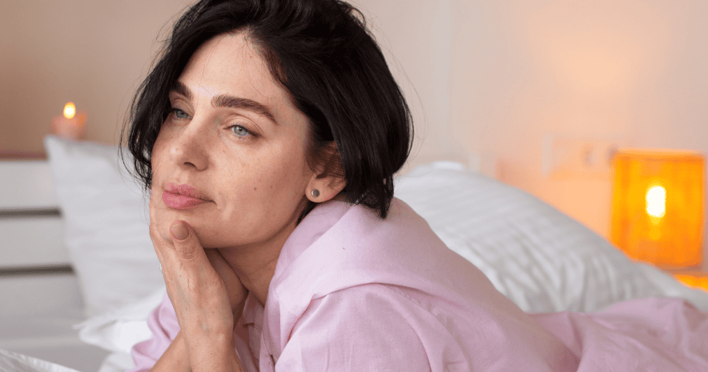 A woman rests her chin on her hand while gazing thoughtfully into the distance, reflecting the lingering mental echoes of a difficult history.