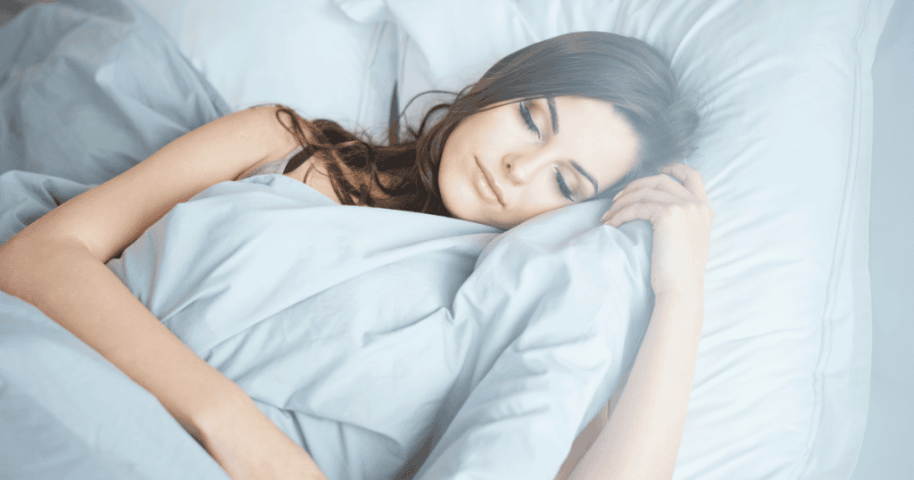 A woman sleeps peacefully in a bed of white linens, capturing the quiet moment when the mind begins to process hidden experiences.