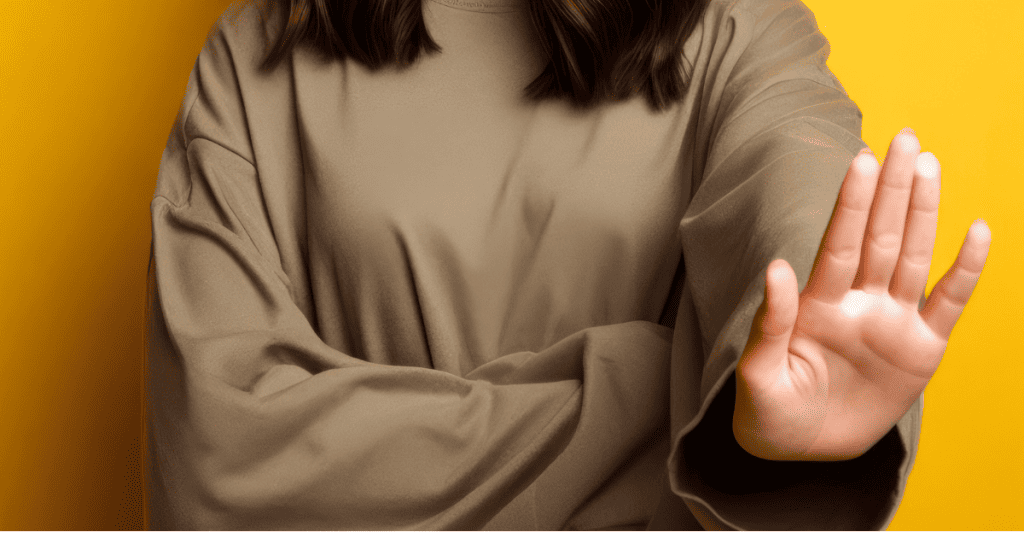 A person holds up a hand in a firm stop gesture, establishing a clear physical limit that stands on its own without need for excuse.