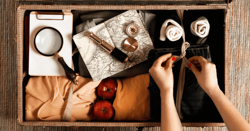 An open vintage suitcase is meticulously packed with clothing and navigation tools, suggesting a readiness to depart at a moment’s notice.