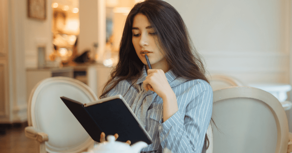 A woman sits calmly with a notebook and pen, depicting the quiet power of shifting your focus inward to document your reality rather than feeding the conflict.