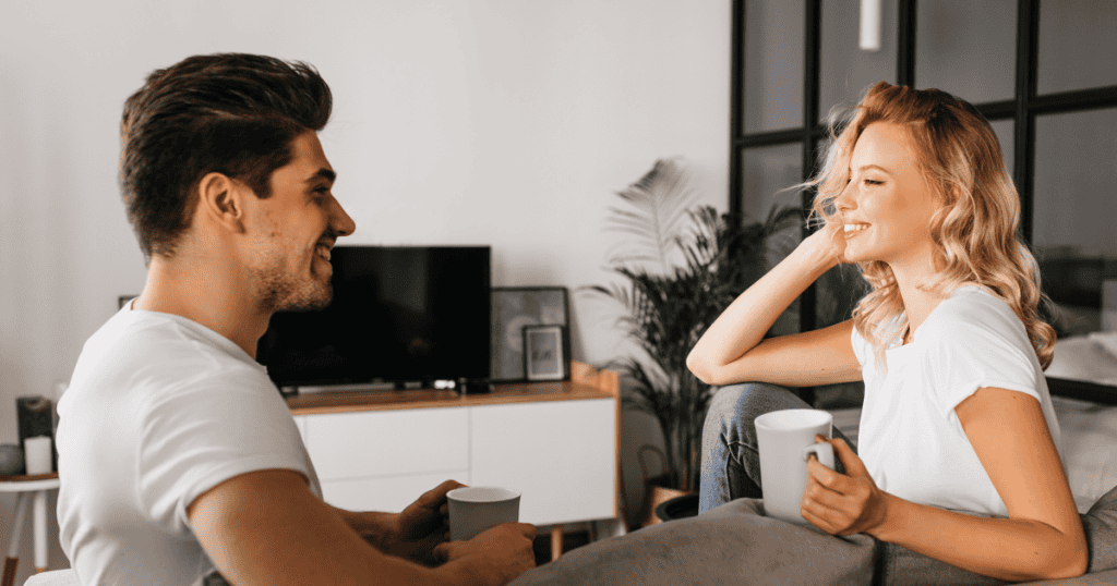 A man and woman sit comfortably in a living room engaging in conversation, creating the space to learn about one another without rushing the process.
