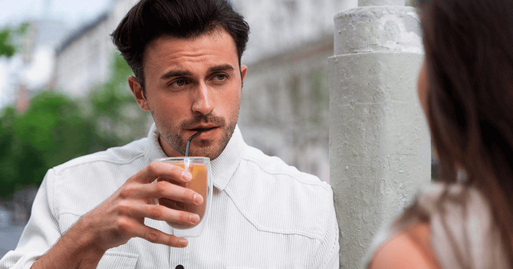 A man casually sips a drink while staring nonchalantly at his partner, demonstrating the unsettling indifference and lack of empathy that often greets a return.