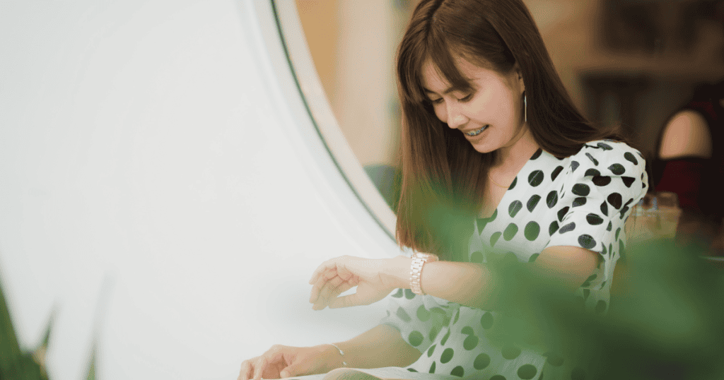 A woman smiles while checking her watch in a brightly lit room, reflecting a newfound sense of personal agency over her own schedule.