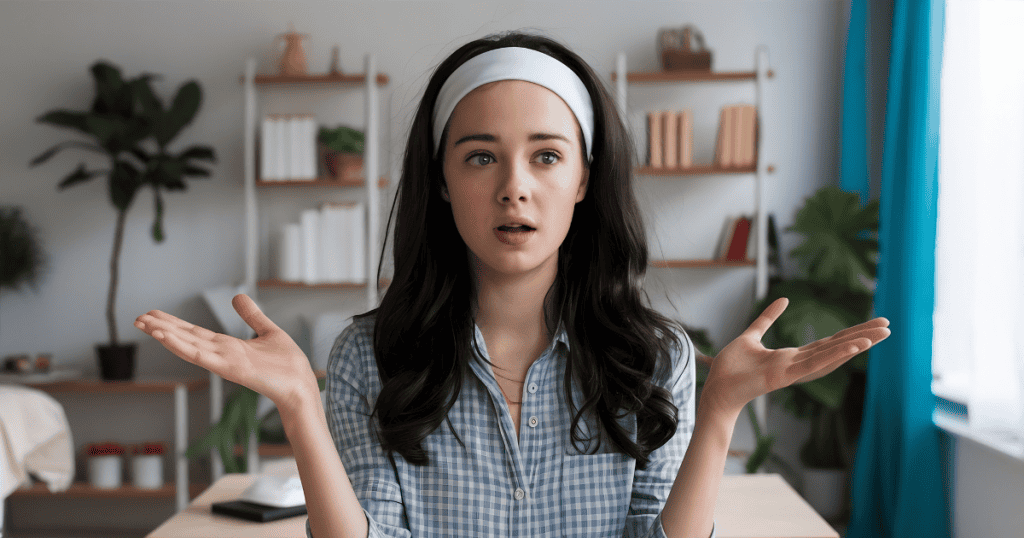 A young woman stands with her hands raised in confusion, capturing the moment reality feels like it is slipping away.