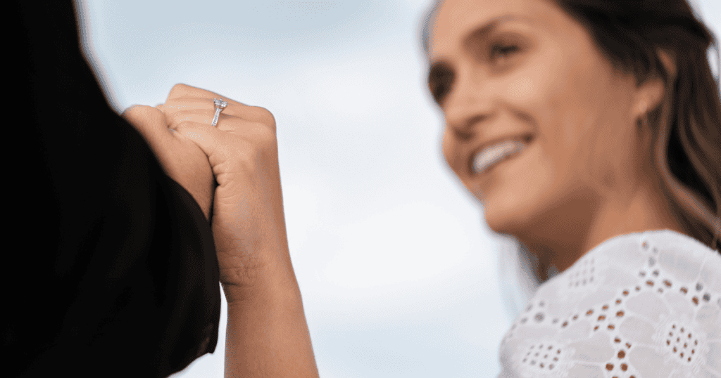 A close-up shows a hand wearing a diamond ring held firmly by another, symbolizing the final moments before a significant personal release.
