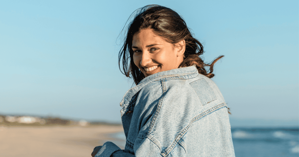 A woman looks back over her shoulder with a bright, carefree smile, reflecting the lightness of a spirit that is no longer useful to keep bound.