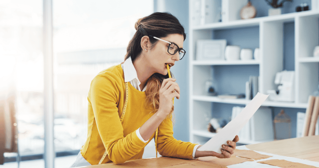 A woman in a yellow sweater focuses intently on a document while biting a pencil, showing the type of deep analytical drive that can be redirected by a calculated cycle.