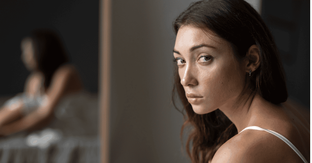 A woman looks over her shoulder with a wary and determined gaze, highlighting the tension and courage required to finalize a high-stakes departure.