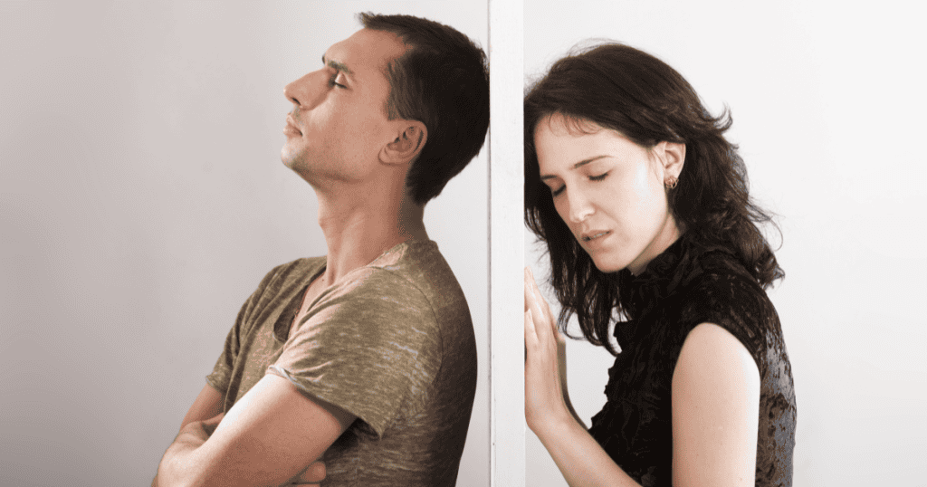 A man and woman stand back-to-back against a wall, eyes closed and emotionally distant, capturing the lingering tension and unresolved pain that can make it difficult to move on years after narcissistic abuse.