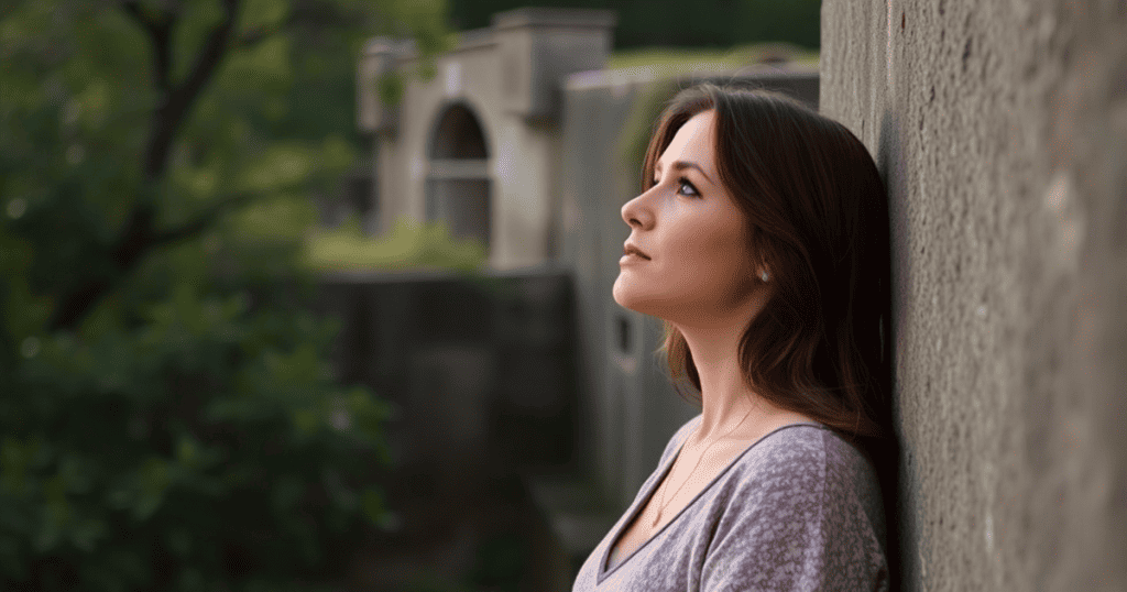 A woman leans her head against a stone wall and gazes upward with a calm, clear expression, signaling the moment her internal narrative finally aligns with the external reality.