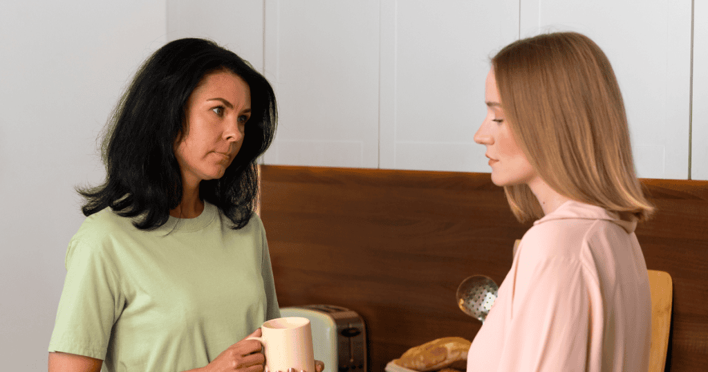 A woman in a green shirt stares blankly at her companion in a kitchen setting, embodying the silent emotional withdrawal that happens when a person feels unheard.