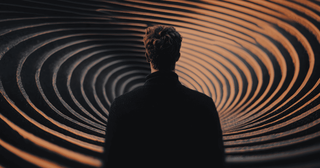 A dark silhouette of a person faces a deep, swirling vortex of concentric rings, suggesting a quiet descent into an environment that swallows one's individual presence.