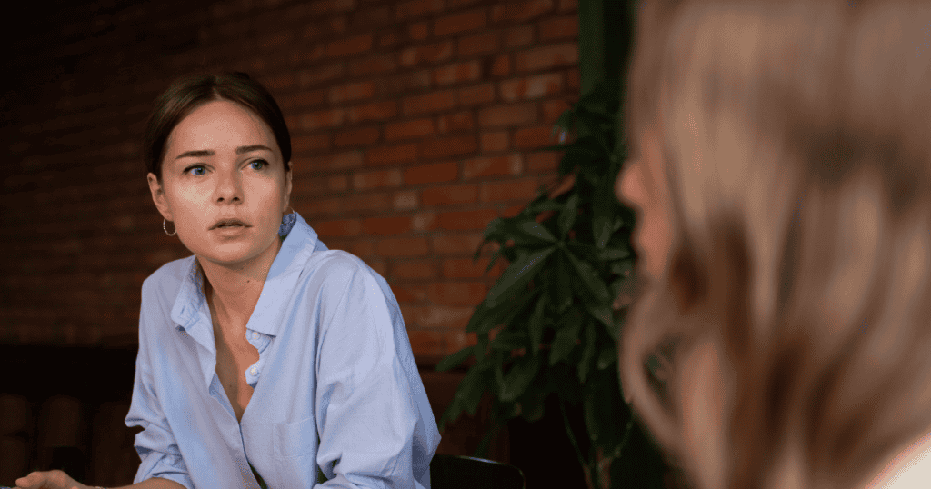 A woman listens intently with a concerned and slightly weary expression, feeling the weight of a relationship where her presence feels secondary.