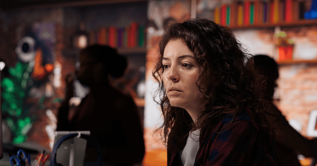 A woman looks off to the side with a pensive and clouded expression, lost in a quiet struggle that others might easily misinterpret as mere shyness.