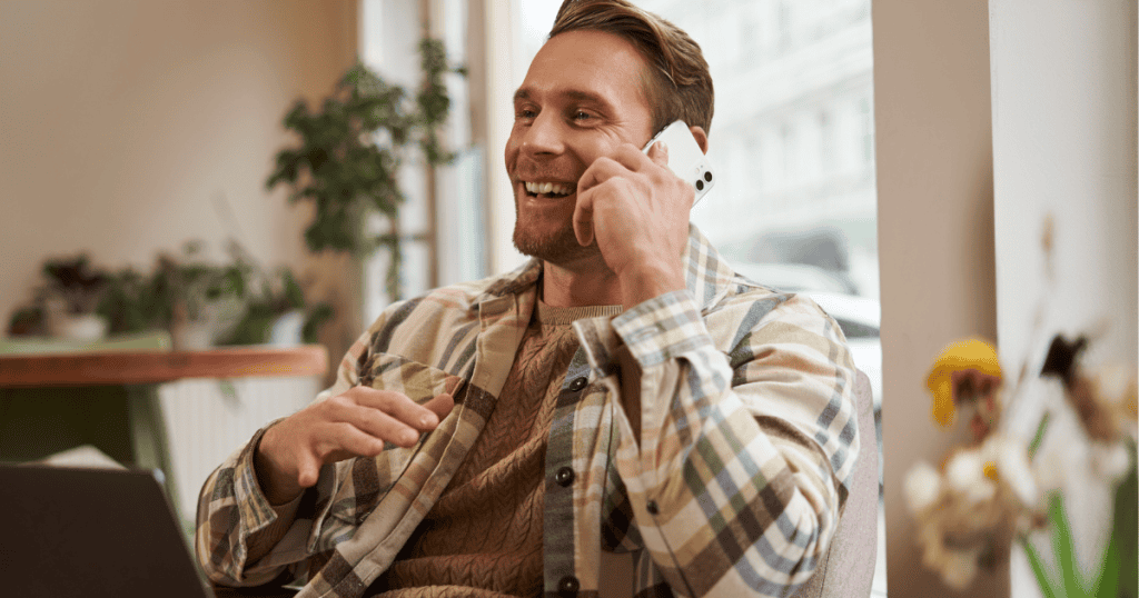 A man laughs brightly while talking on his mobile phone, contrasting a public persona with the complex emotional mechanics hidden beneath the surface.