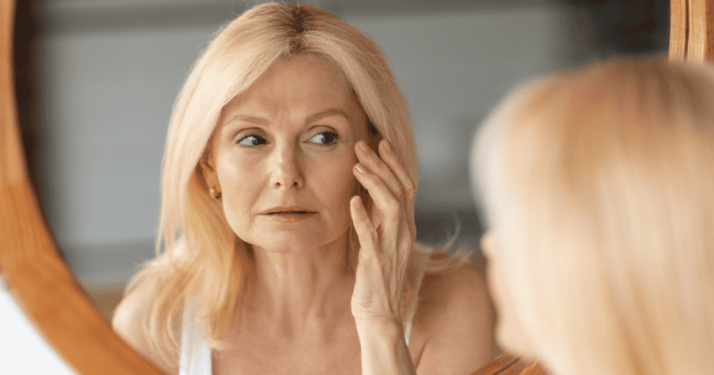 A blonde woman examines her reflection in a circular wooden mirror, highlighting an obsessive fixation that deepens as the years pass.