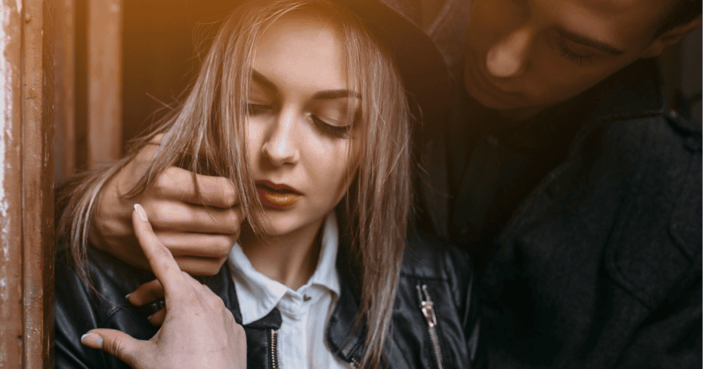 A man tilts a woman's face upward with a hand on her neck while she looks down with a conflicted expression, portraying a sudden, intense display of physical intimacy designed to disrupt her emotional independence.
