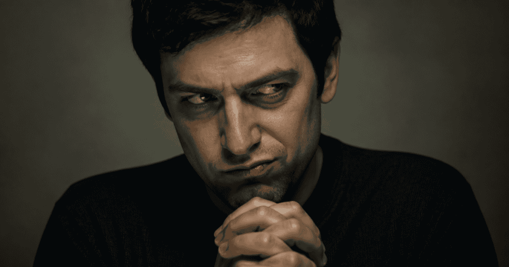 A man clasps his hands tightly together while casting a dark, resentful side-eye look, embodying what malicious envy really means in narcissism.