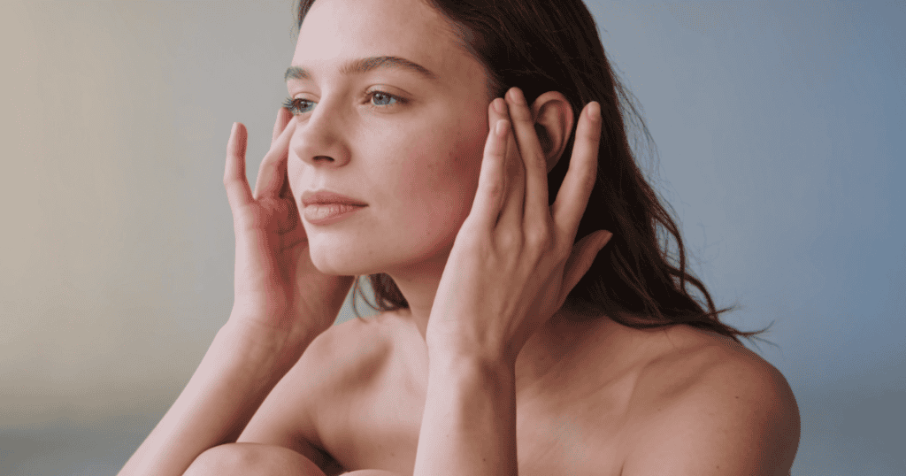 A calm woman gently touches her face while looking away thoughtfully, highlighting how your complete emotional detachment can disarm an abuser.