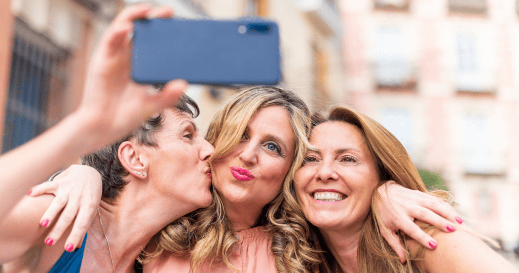 Three women laughing and taking a selfie together, showing that healing from narcissistic abuse is less about searching inward and more about actively re-engaging with joy and connection.